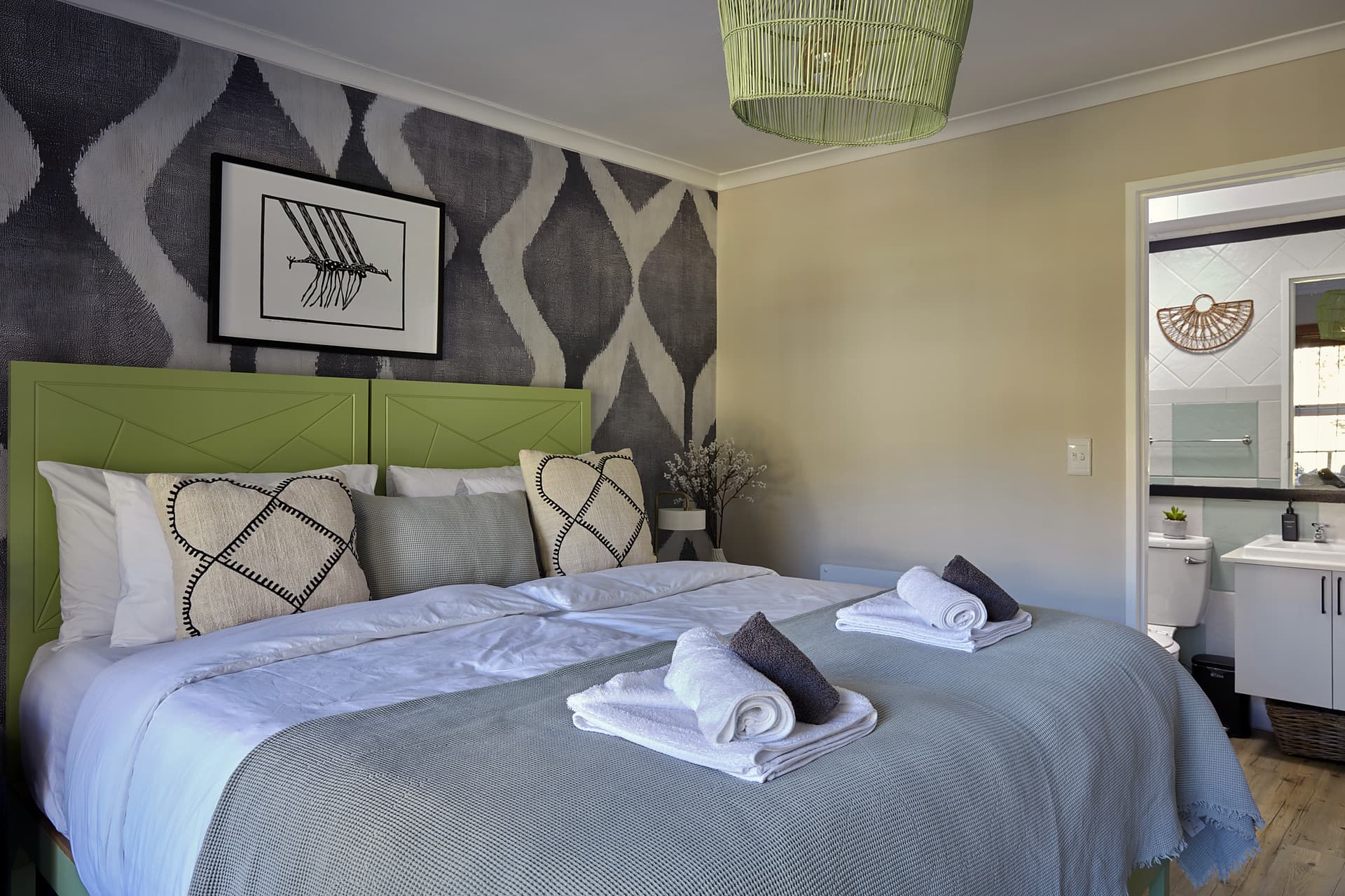 Gardens – Main bedroom looking through to the en-suite, green headboards and a waffle blanket across the bed