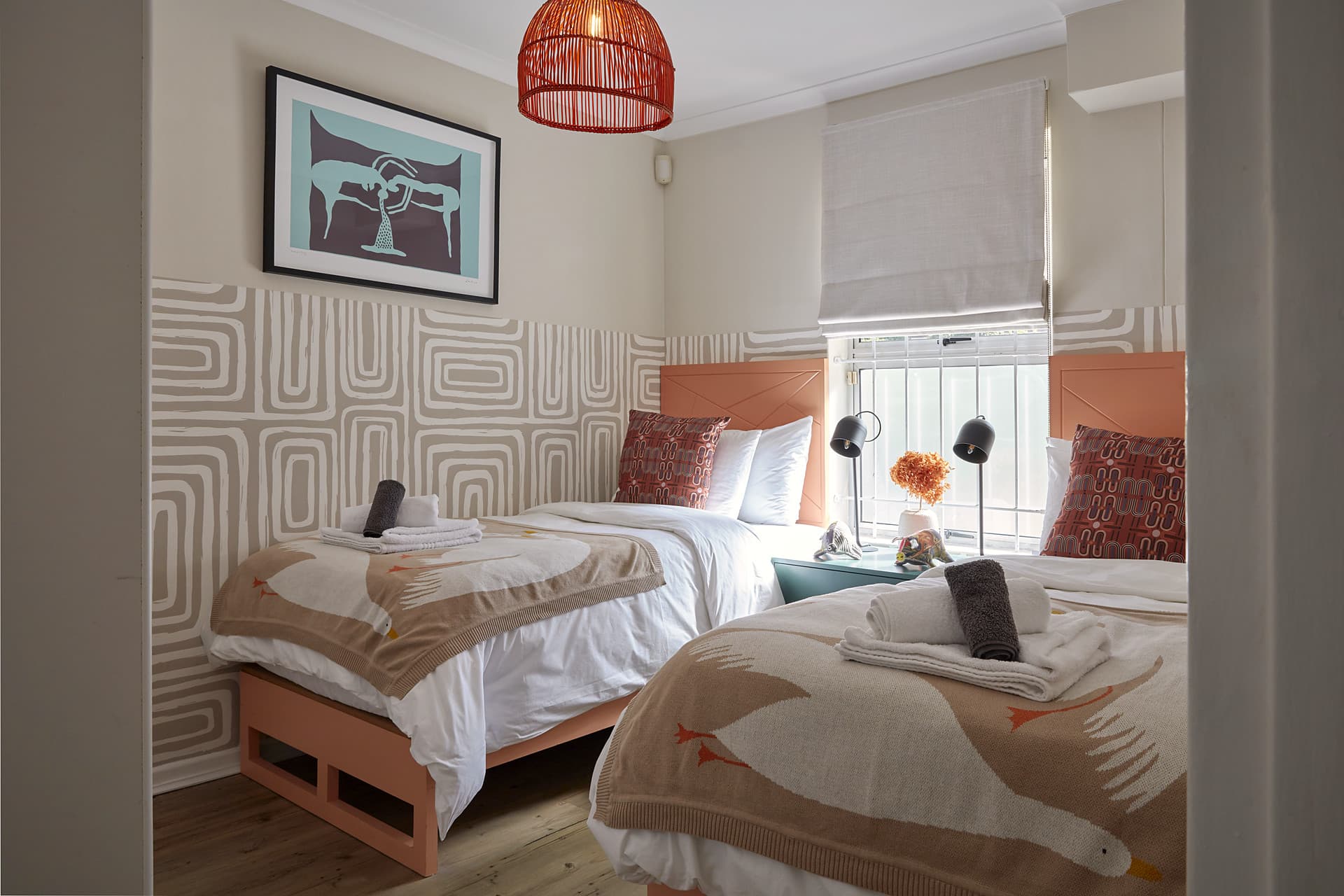 Gardens – Twin bedroom with terracotta headboards, a patterned half-wall and a red woven pendant