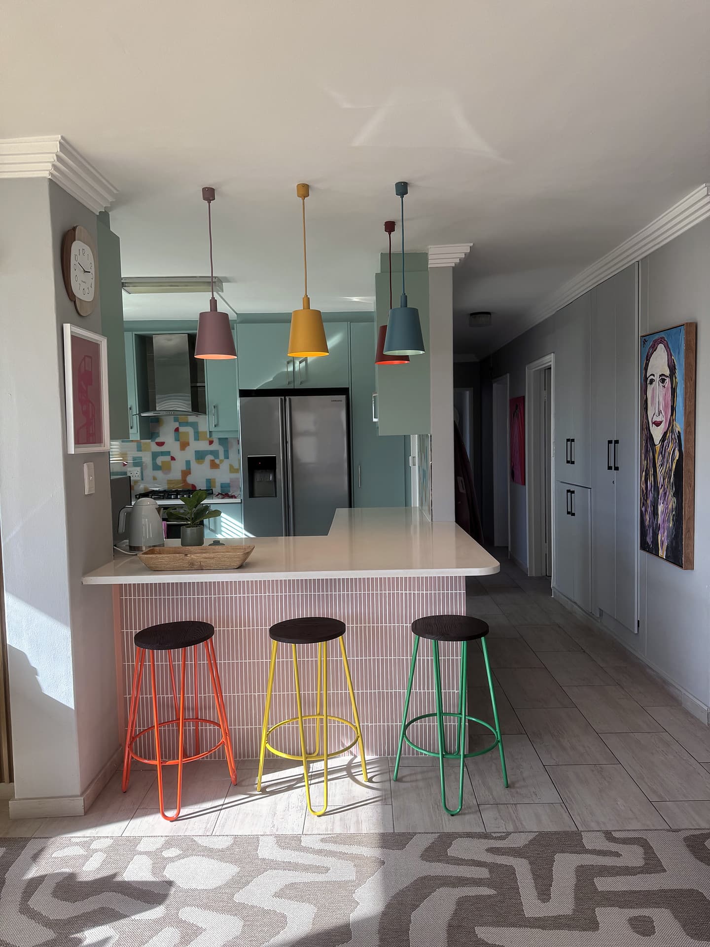 Strand – Kitchen from the living side, stools in a row, painting on the wall