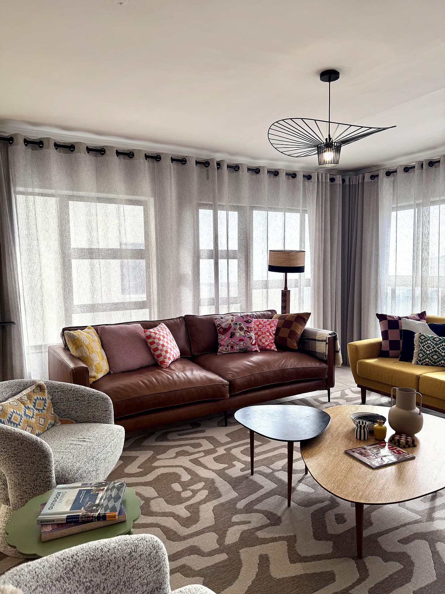 Strand – Two sofas and a patterned rug in front of sheer-curtained windows