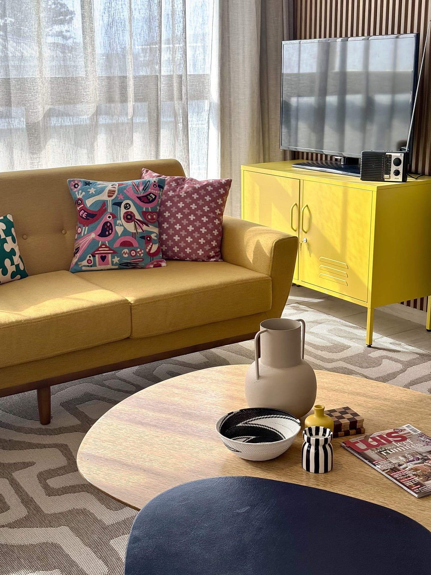Strand – Yellow sofa with patterned cushions beside a yellow cabinet