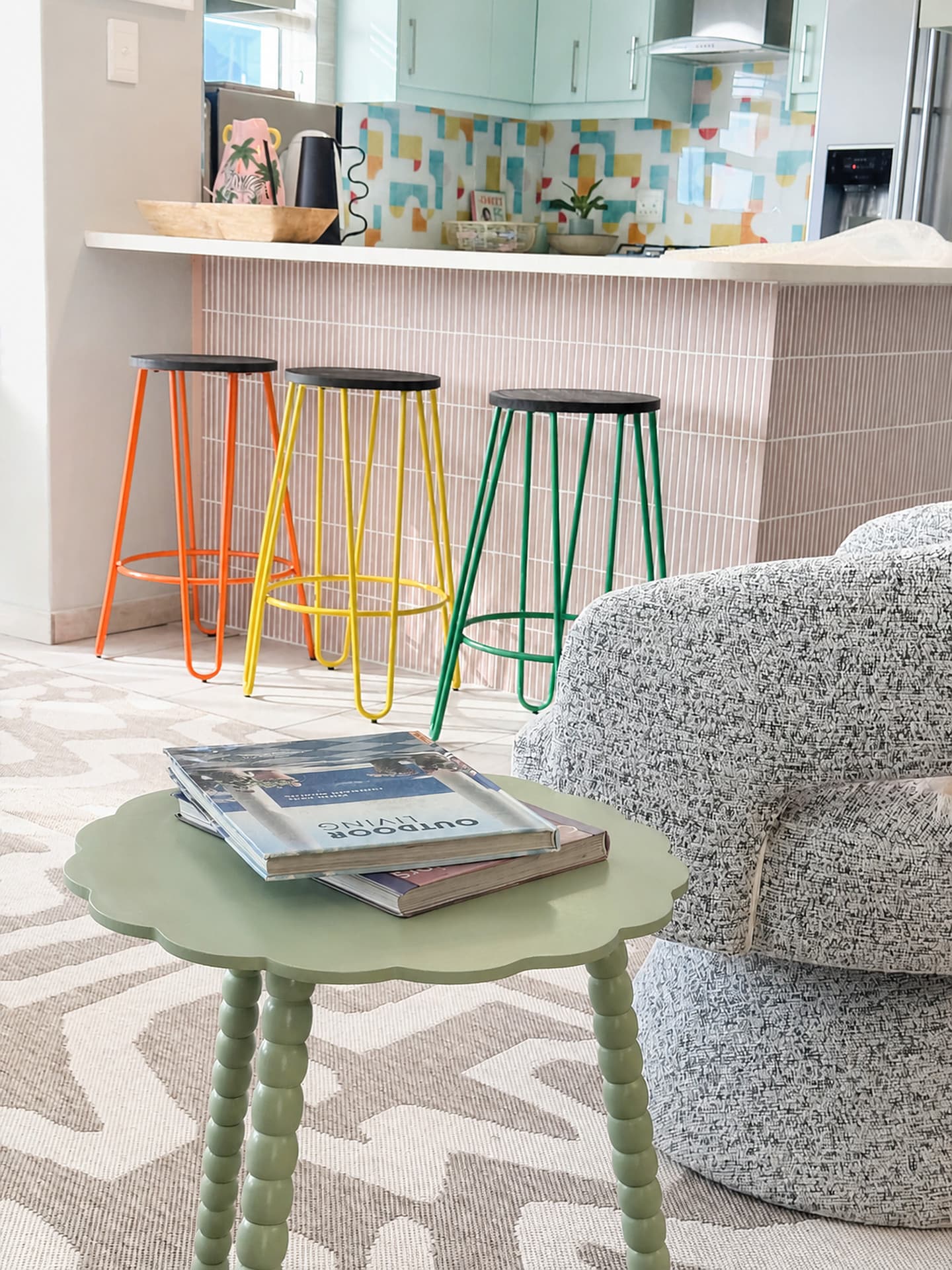 Strand – Boucle armchair, green side table and coloured bar stools at the island