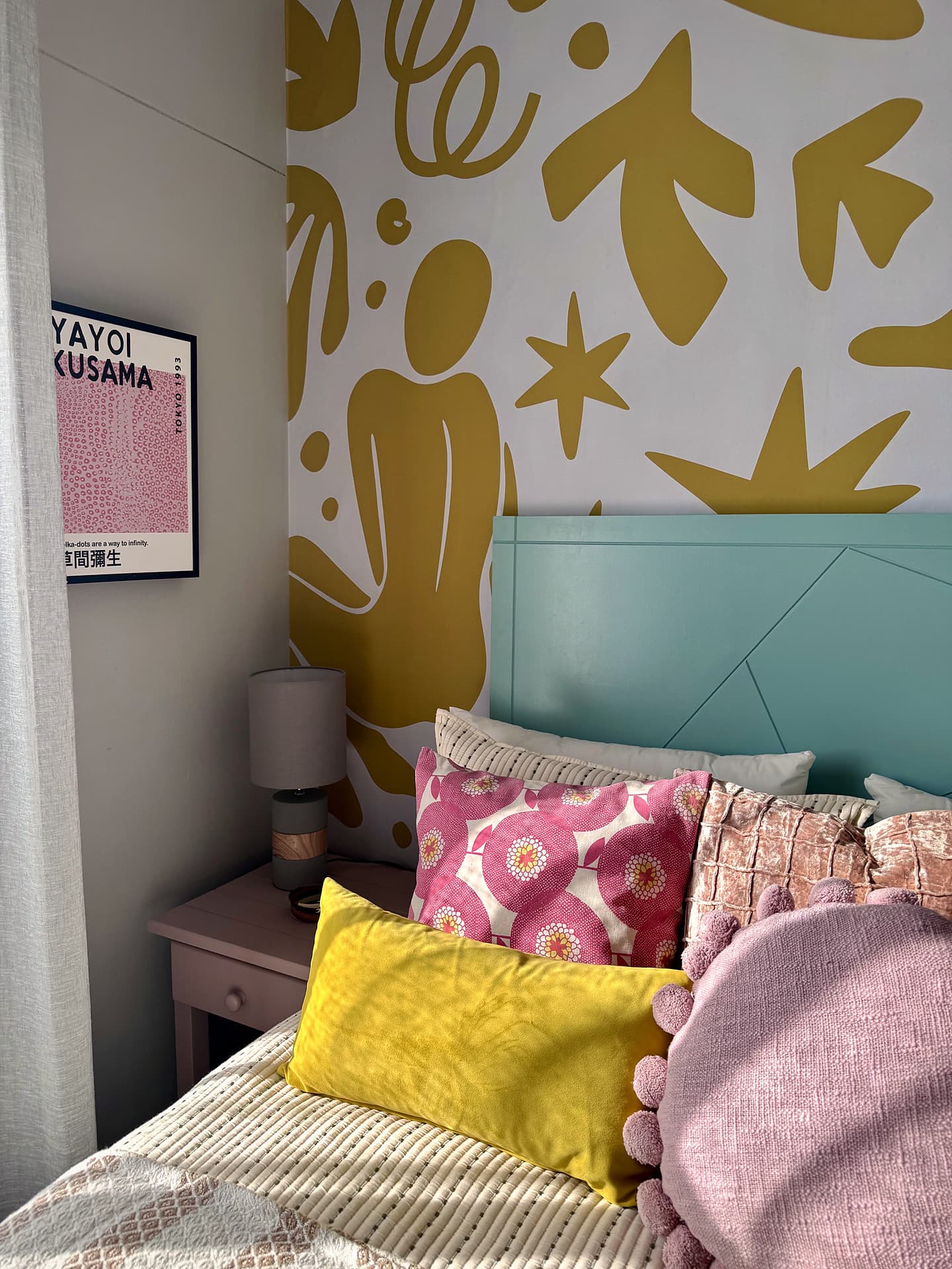 Strand – Teal headboard against a mustard mural, pink and yellow cushions