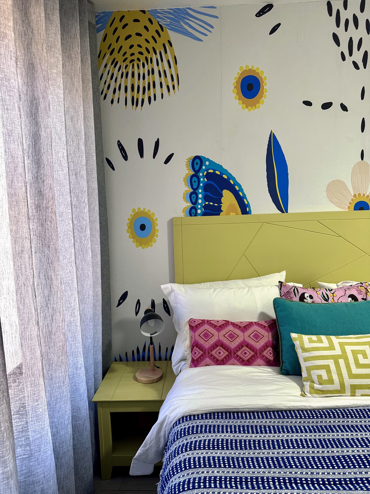 Strand – Lime headboard against a butterfly mural, patterned cushions