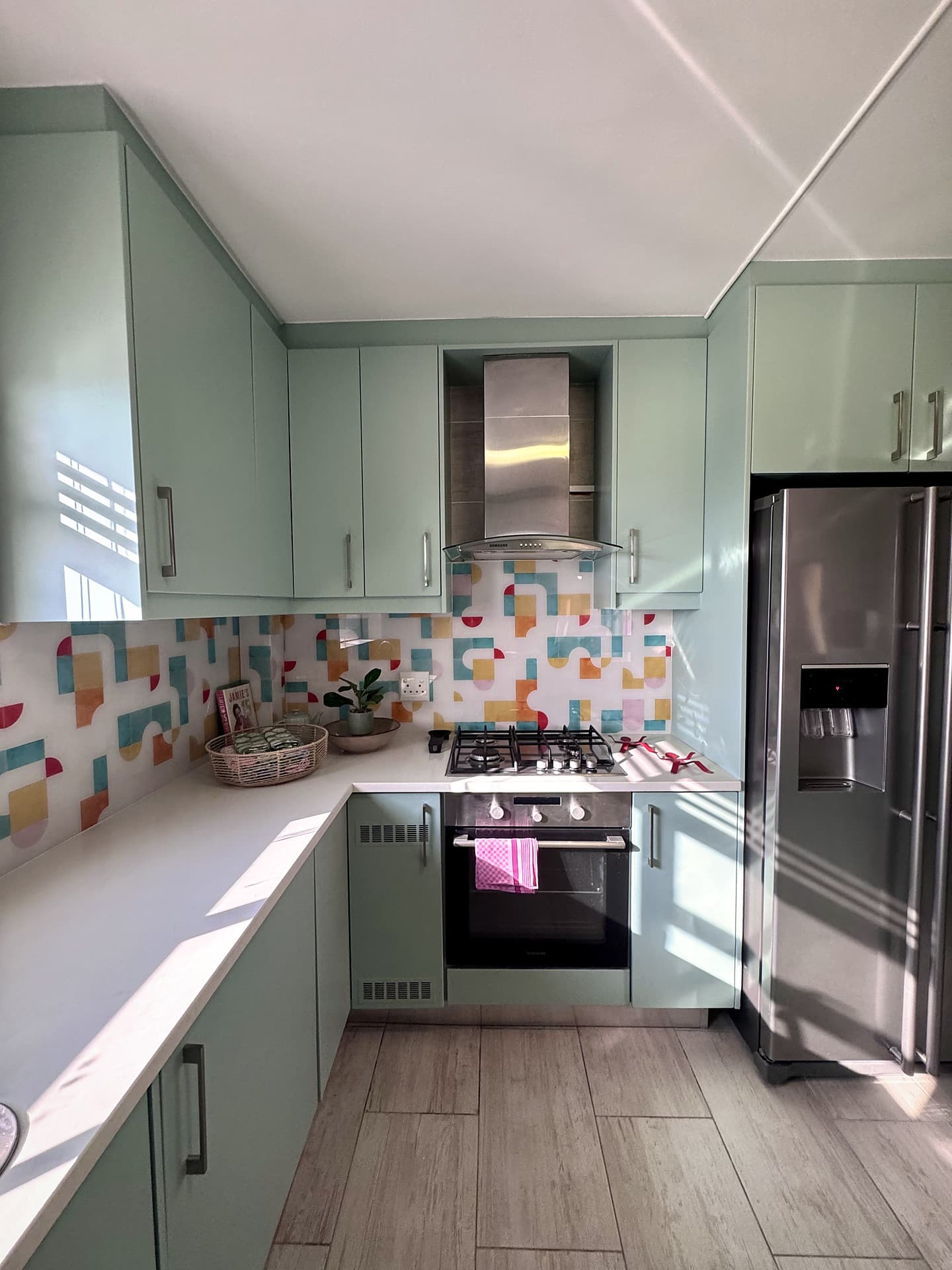 Strand – Mint-green kitchen with a patterned splashback and stainless fridge