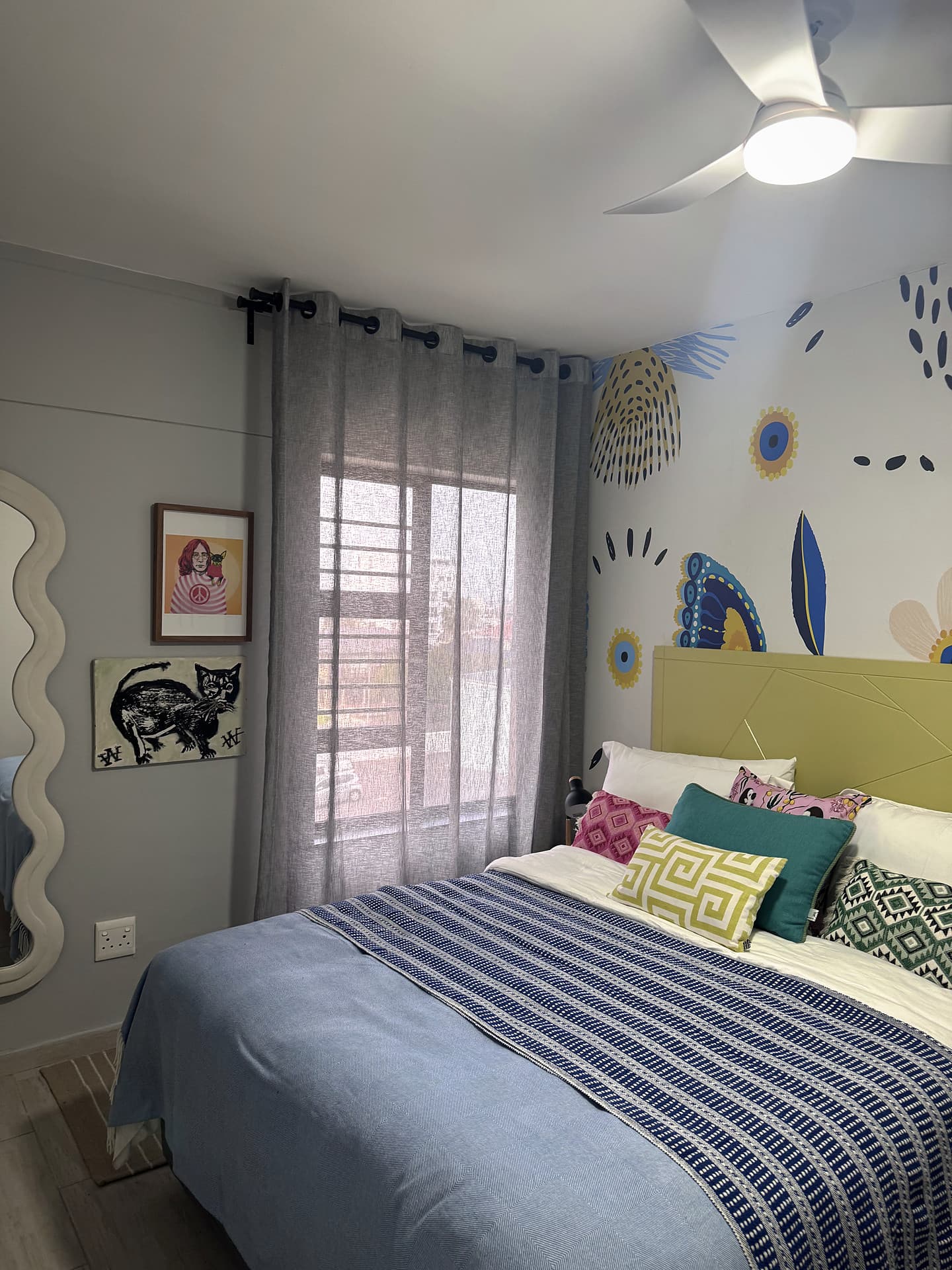 Strand – Bedroom with a lime headboard, butterfly mural, curtains and a wavy mirror