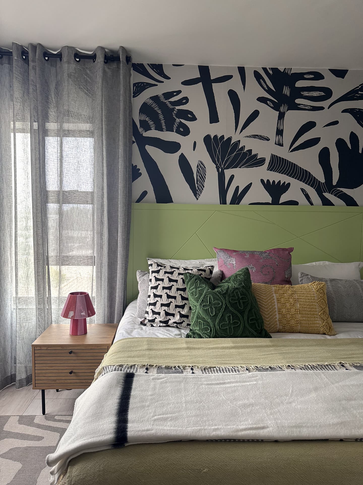 Strand – Bed with a lamp and curtains, navy leaf mural behind