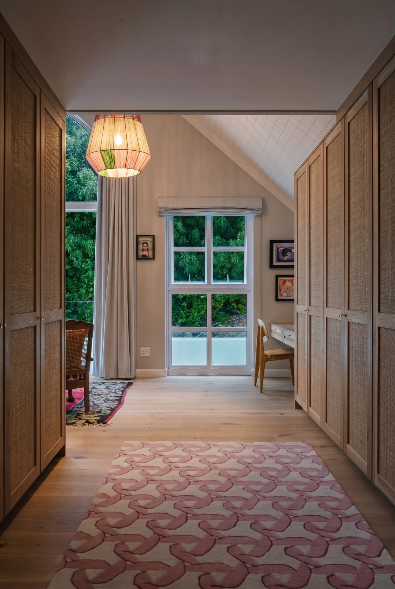 The Kalk Bay dressing corridor: floor-to-ceiling cane-panelled wardrobes on both sides, opening to a window on the garden